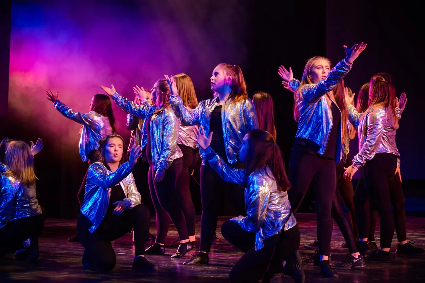 Dreams students performing together under colourful stage lighting