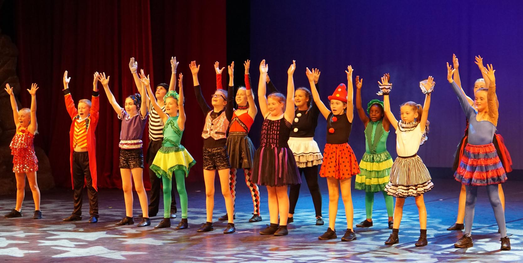 Dreams cast performing a colourful group number on stage